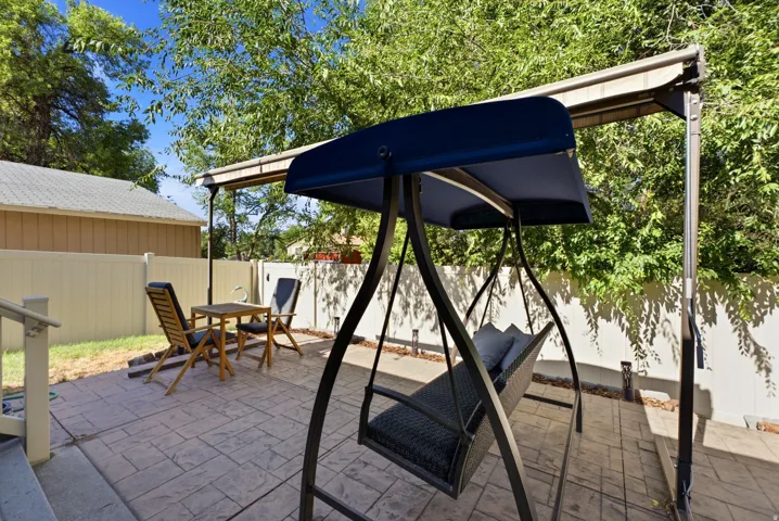 Paved patio area featuring a textured stamped concrete surface, a partial overhead awning, and a privacy fence