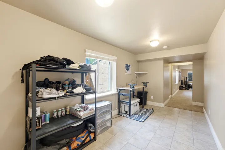 Versatile utility space featuring tile flooring, industrial-style metal shelving with ample storage capacity, recessed ceiling lighting, and direct access to adjoining rooms