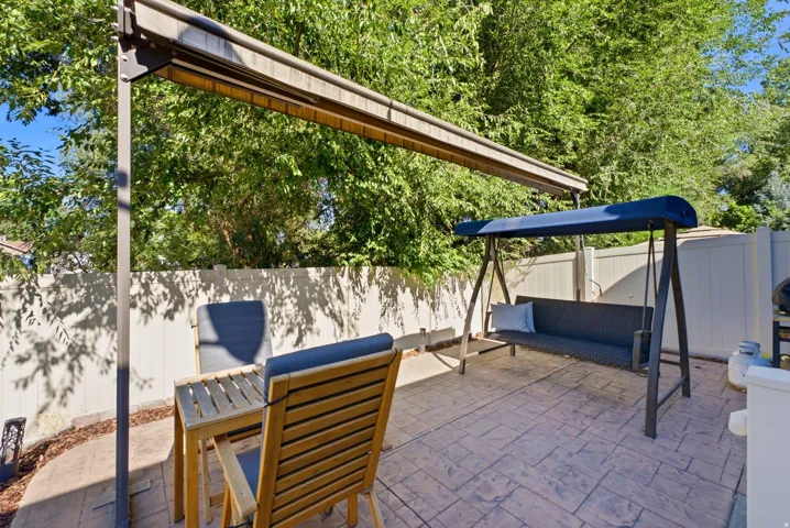 Outdoor entertaining space featuring dual shade structures with retractable canopies, permeable paver flooring, and mature tree coverage