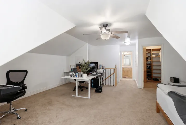Carpeted attic space with a sloped ceiling and white walls