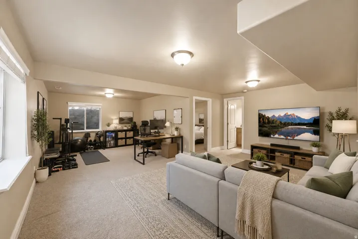 Expansive lower-level space featuring broadloom carpet, multiple light fixtures, and a window with natural light