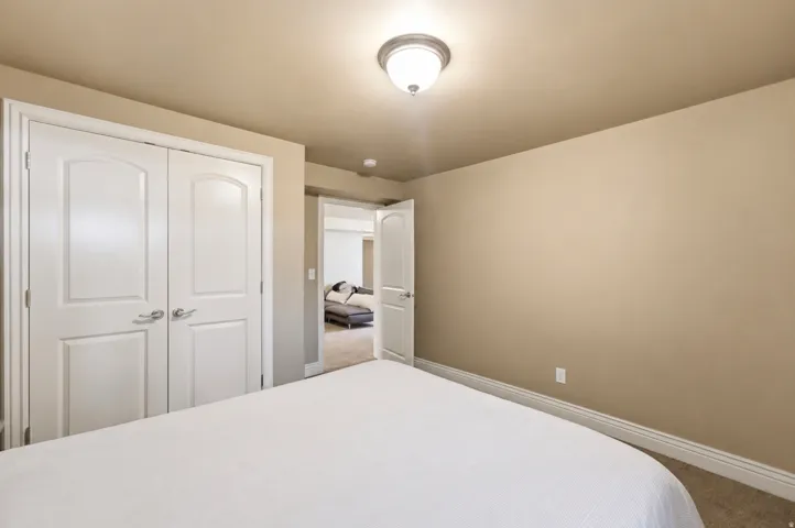 Spacious bedroom featuring neutral wall finishes, recessed ceiling lighting, and dual white panel closet doors with three-panel design