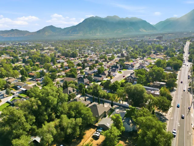 Expansive aerial perspective showcasing the property within a tree-lined residential neighborhood, with mature landscaping throughout the surrounding area