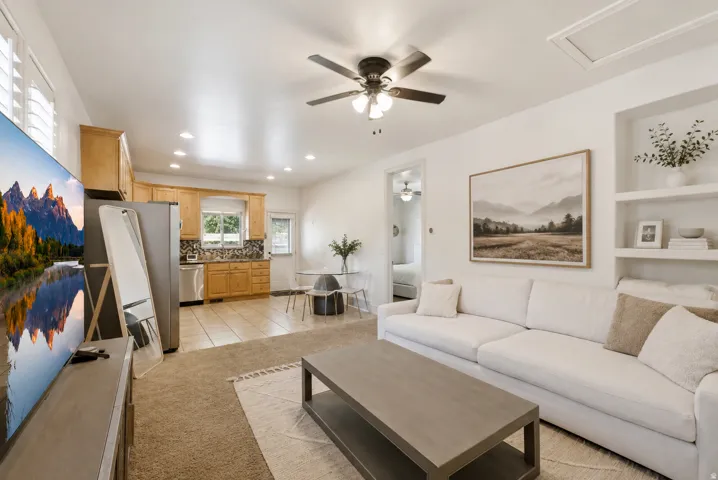 Bright and open living space featuring a contemporary white sectional sofa, wood-finish flooring throughout, and recessed ceiling lighting