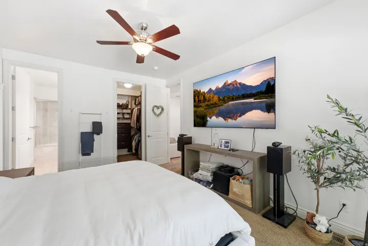 Spacious room featuring a ceiling fan with integrated lighting, wall-mounted television, and carpet flooring