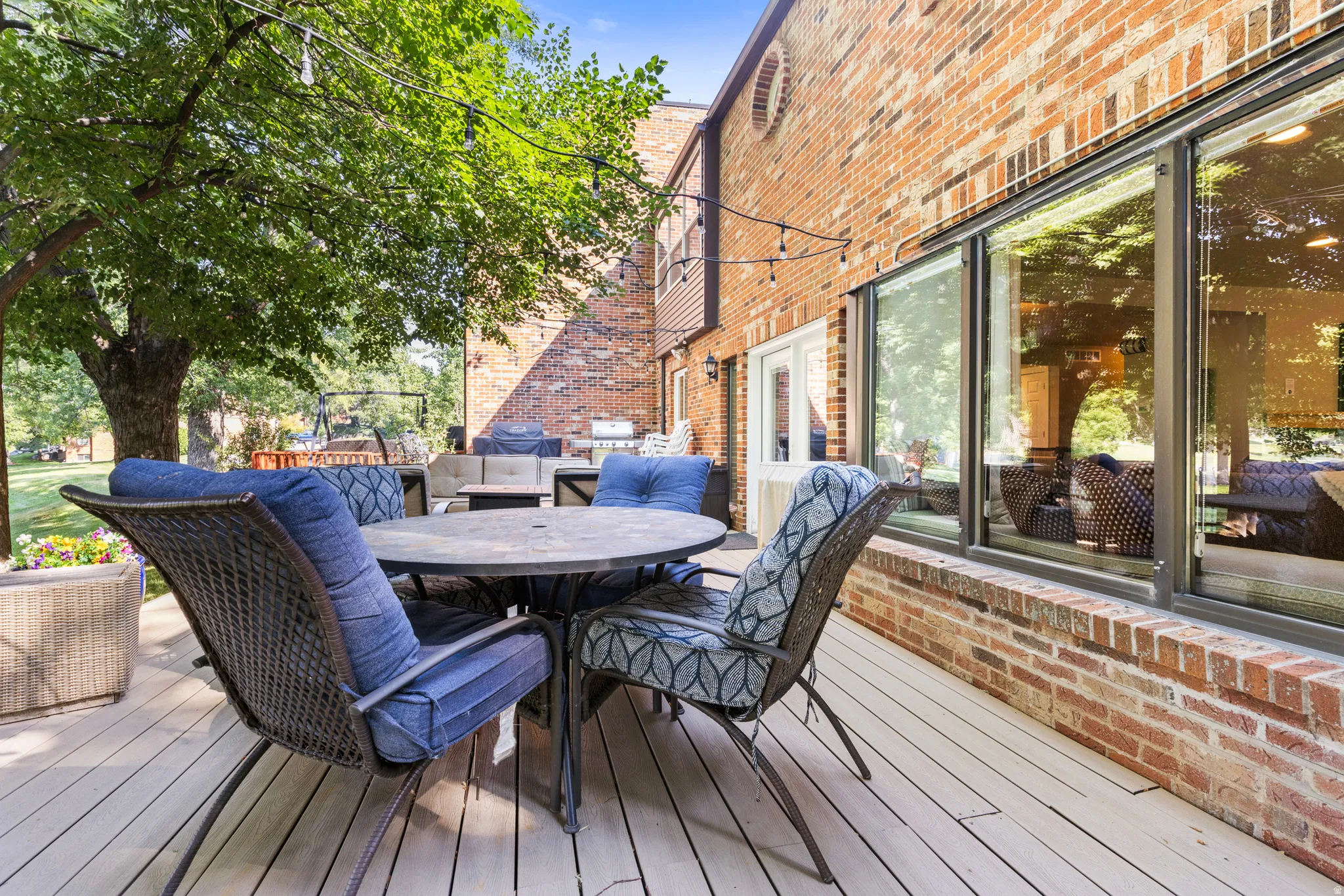 Expansive composite deck with wood-finish flooring overlooking mature landscaping and brick architectural detailing