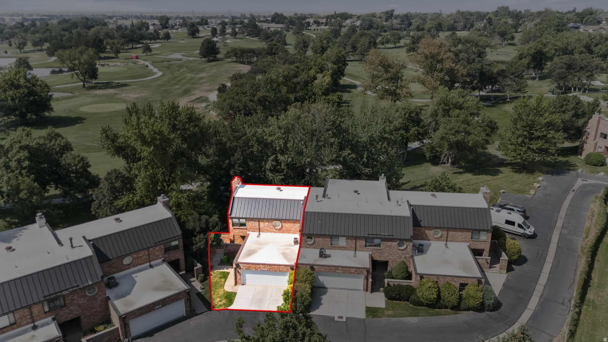 Aerial view showcasing a contemporary multi-structure residence featuring standing-seam metal roofing, clean architectural lines, and integrated landscaping