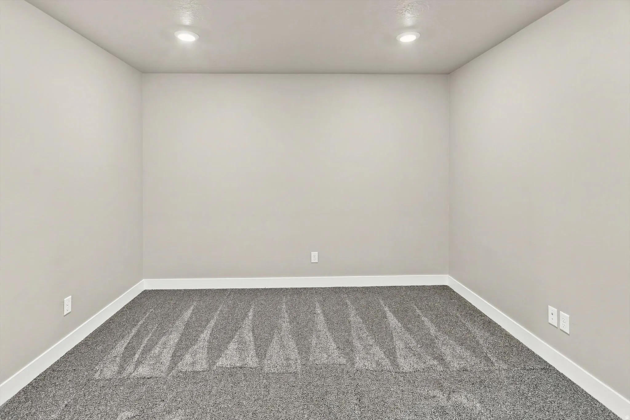 Neutral wall color, recessed lighting, and grey patterned carpet
