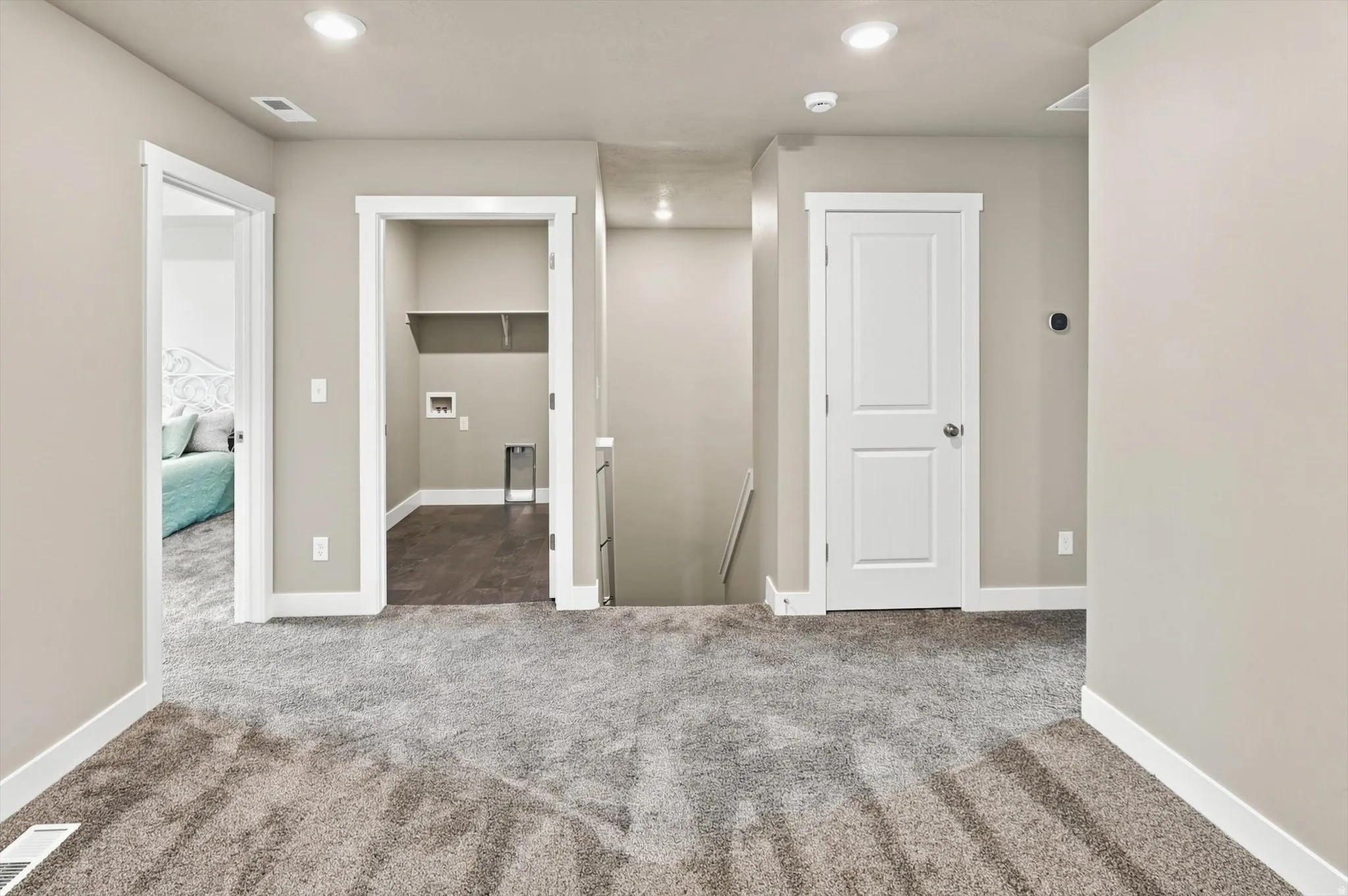 Spacious finished basement featuring neutral carpeting with geometric patterning, recessed ceiling lighting, and multiple white six-panel doors providing access to adjoining rooms