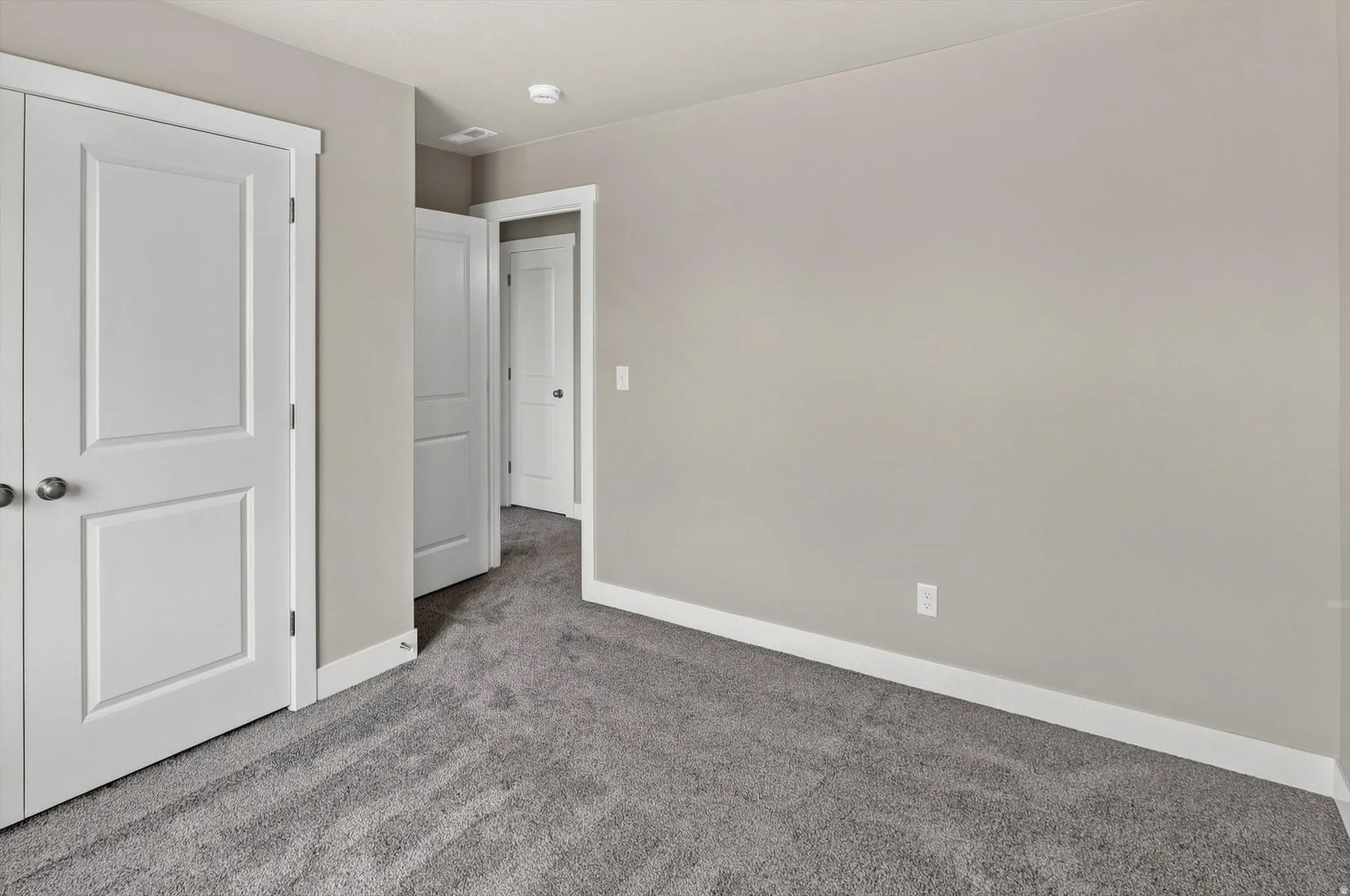 Neutral-toned walls complement plush grey carpeting