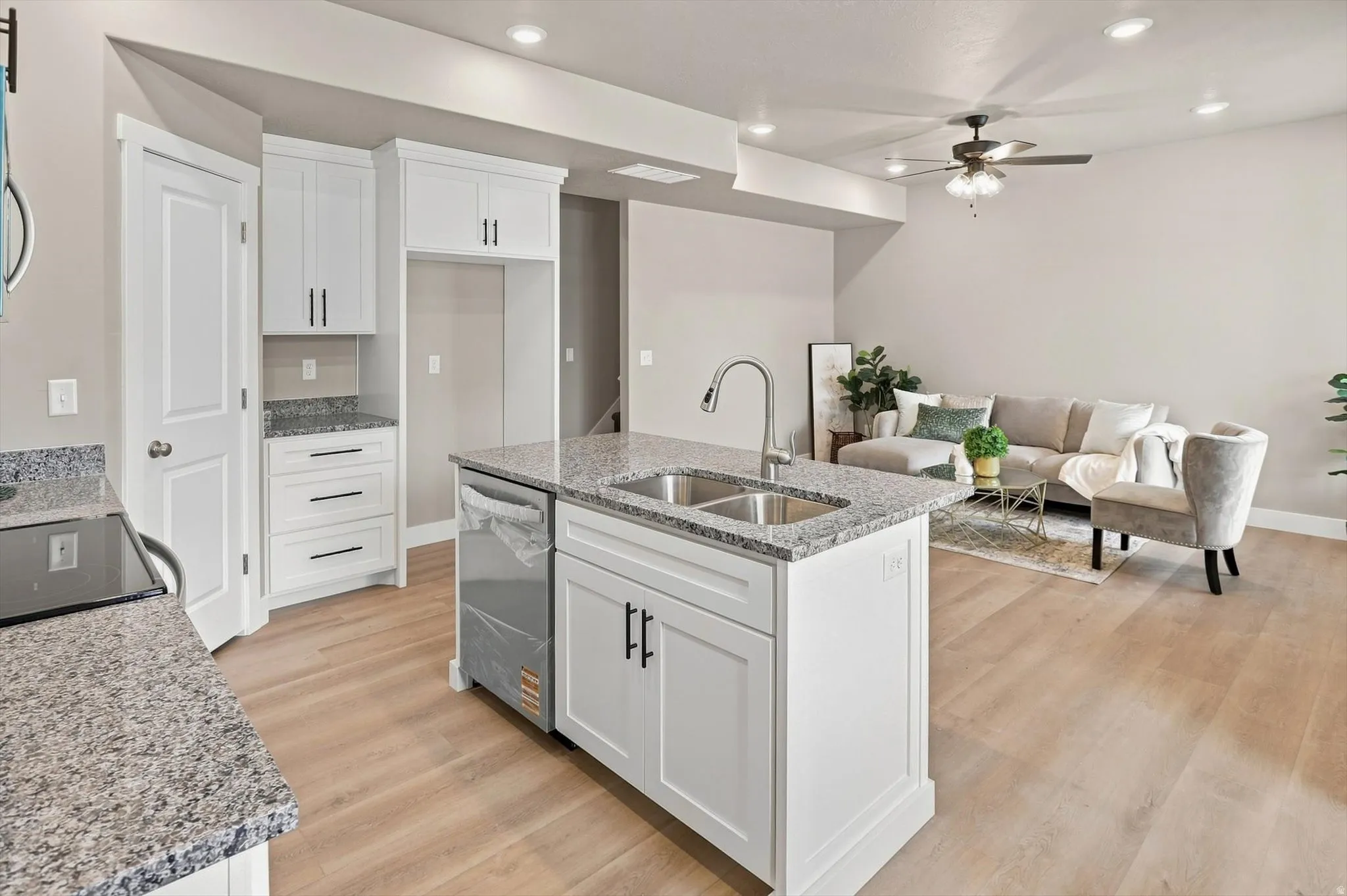 Kitchen with white cabinetry, granite countertops, and wood-finish flooring