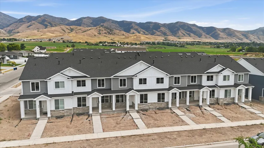 Modern townhome community featuring clean-lined architectural design with mixed exterior finishes of dark and light siding, multi-car driveways with concrete pads, and pitched rooflines with dark asphalt shingles