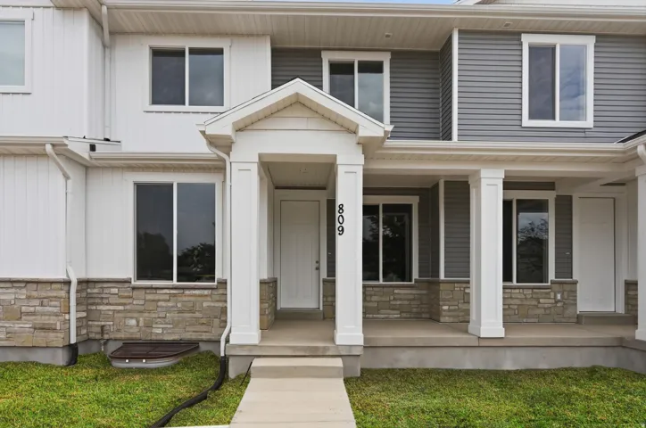 Multi-unit residence featuring a covered entry, stone veneer and siding facade, and multiple windows