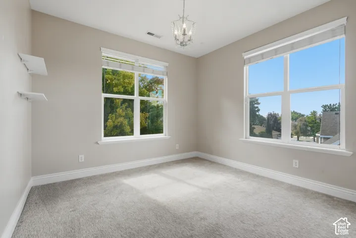 Recessed lighting, large dual pane windows, overhead chandelier, light-toned walls, and carpeted flooring