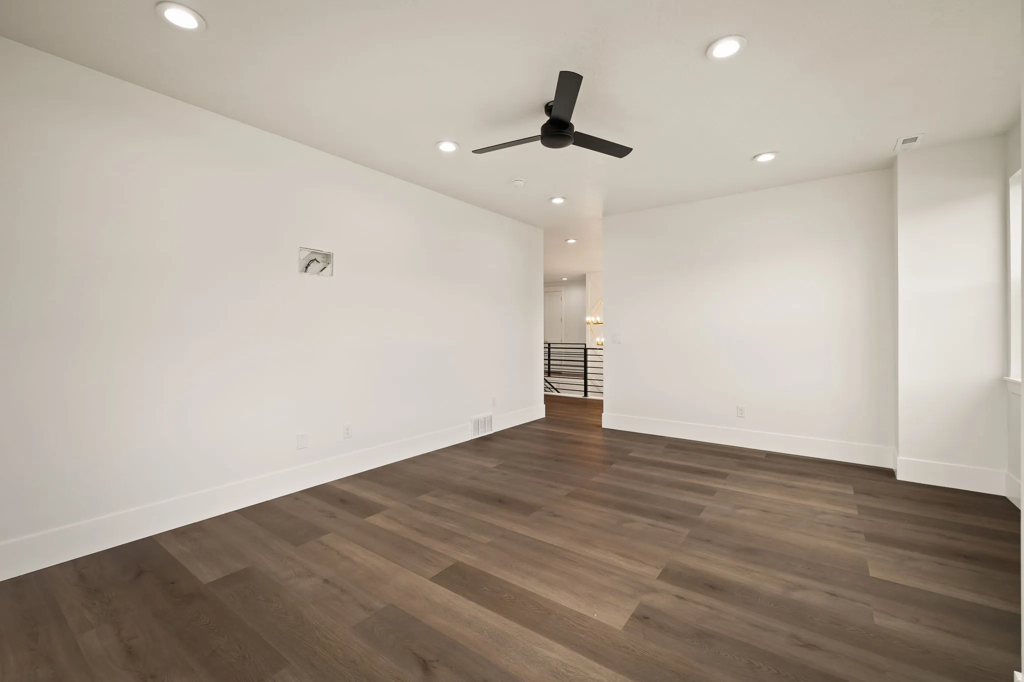 Spacious room featuring wood-finish flooring, recessed lighting, a ceiling fan, and white baseboards