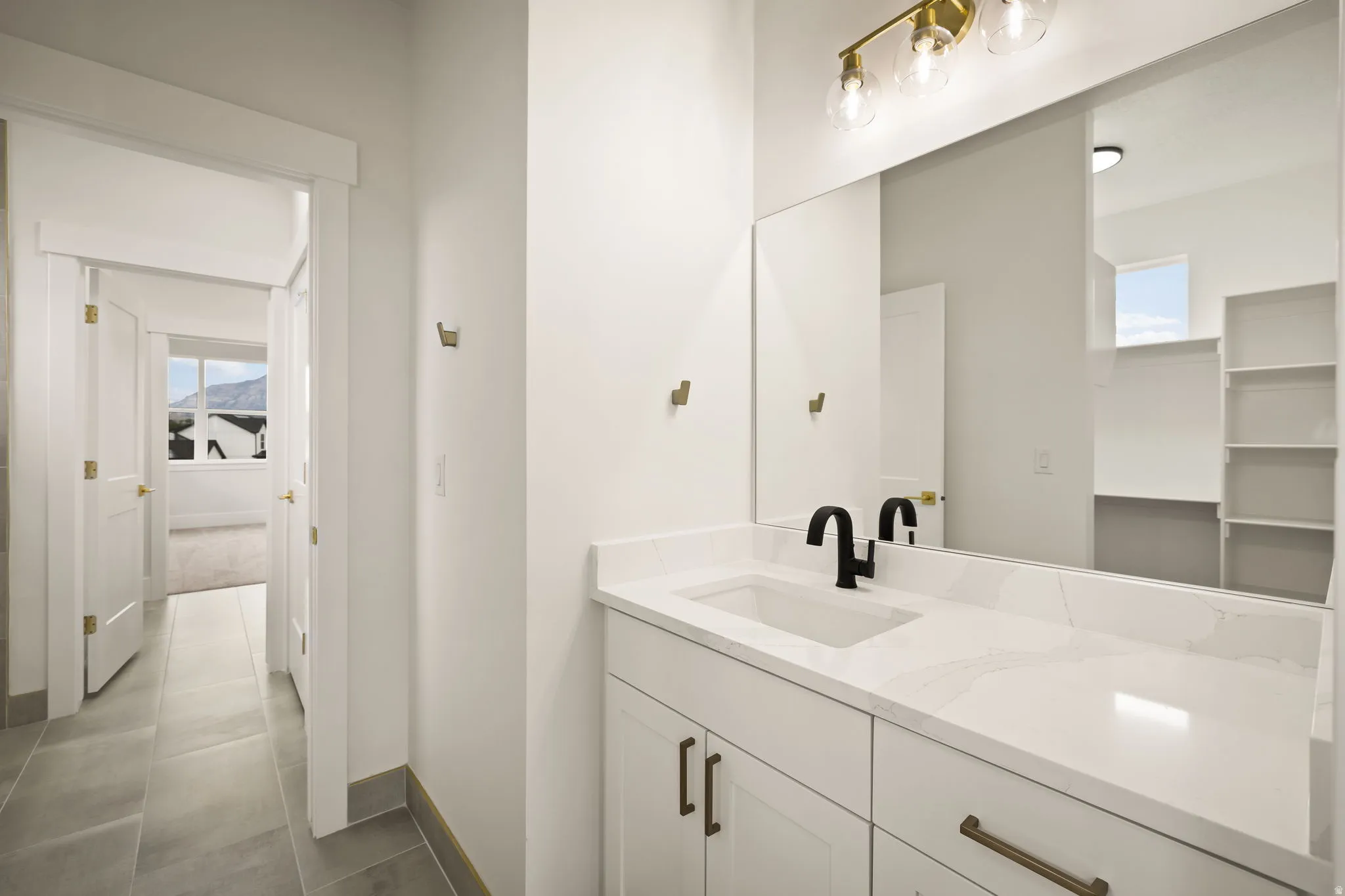 Bathroom vanity with a white countertop and integrated sink, matte black faucet, and brass-tone hardware