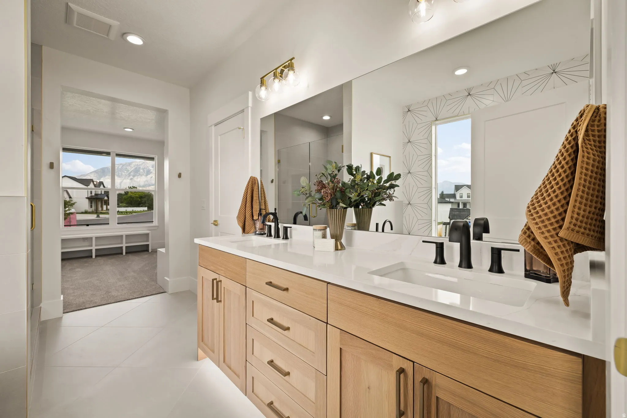 Dual vanity featuring light wood-finish cabinetry, white countertop, and matte black fixtures
