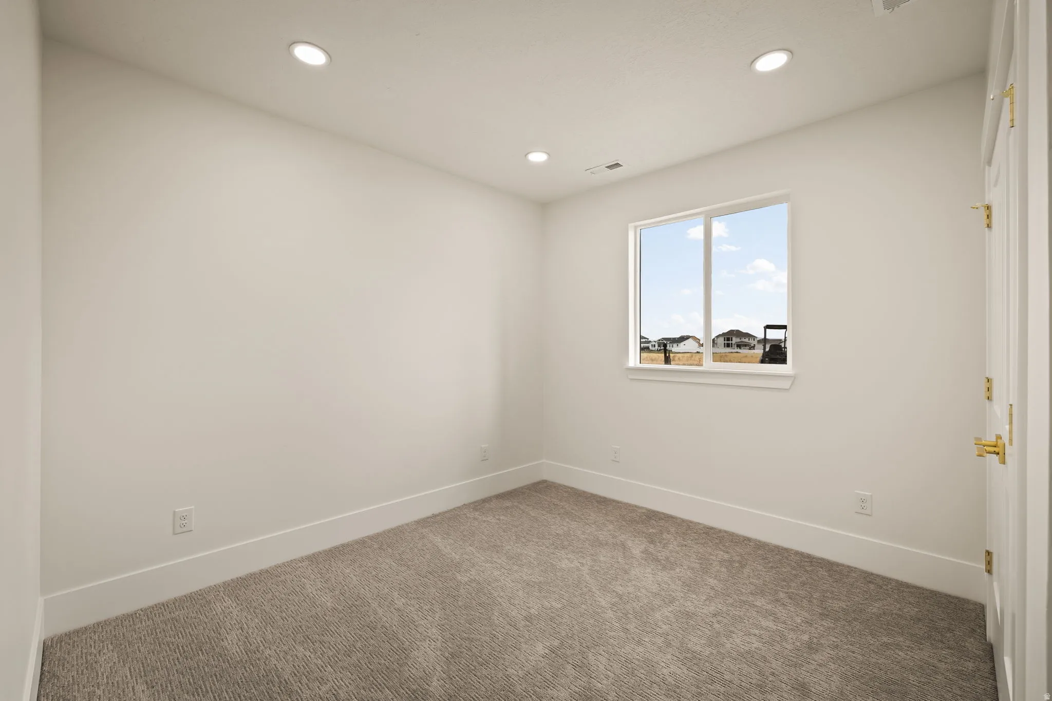 Carpeted room with recessed lighting and a double-pane window
