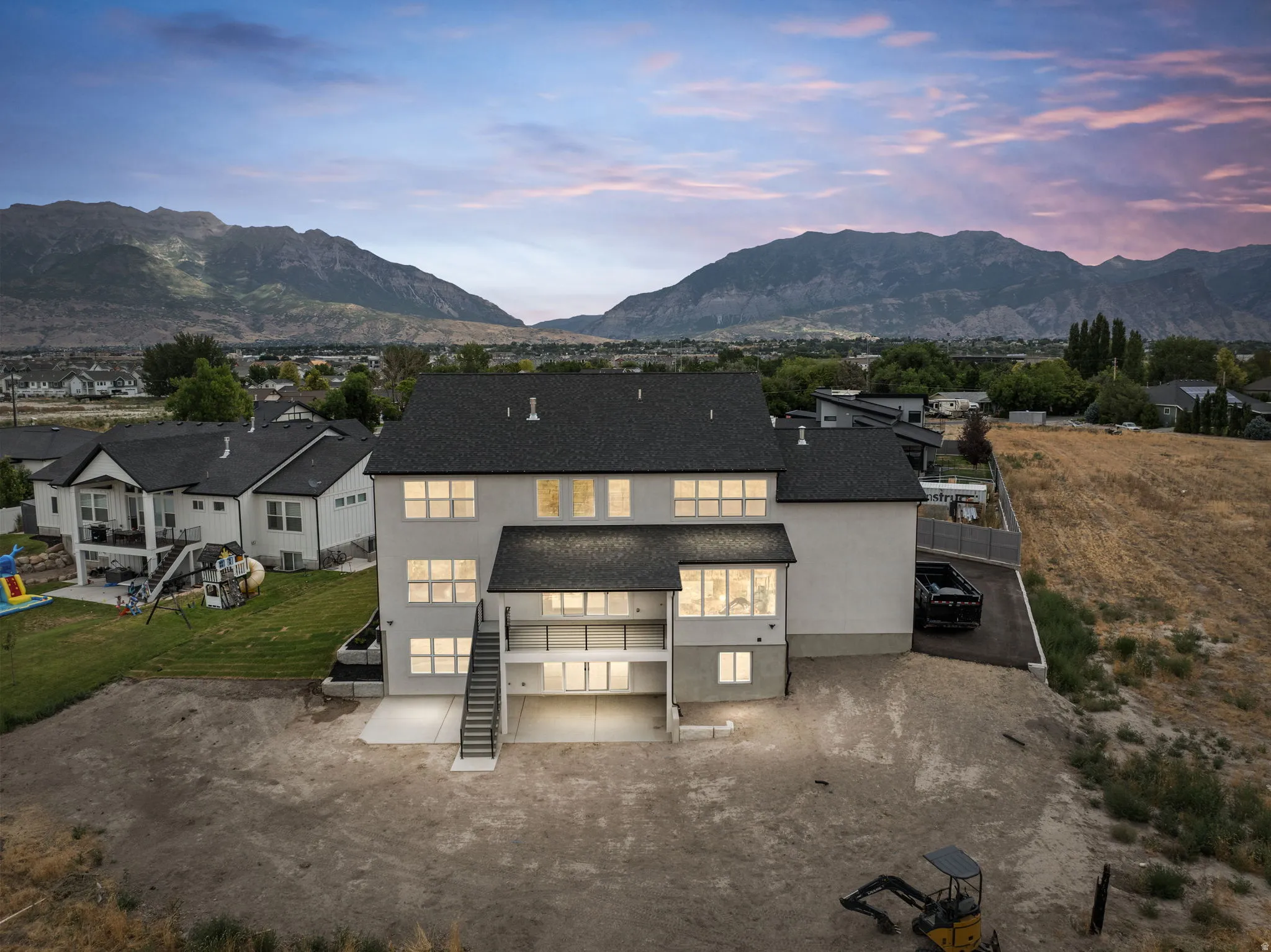 Contemporary residence featuring a dark shingle roof and light-toned exterior siding