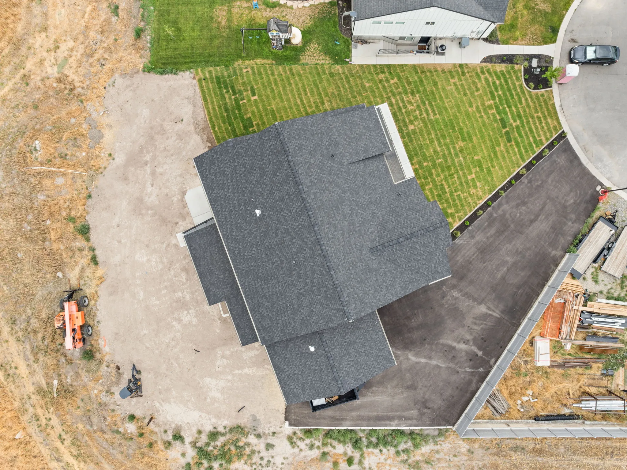 Newly constructed home featuring a dark shingle roof and a spacious paved driveway