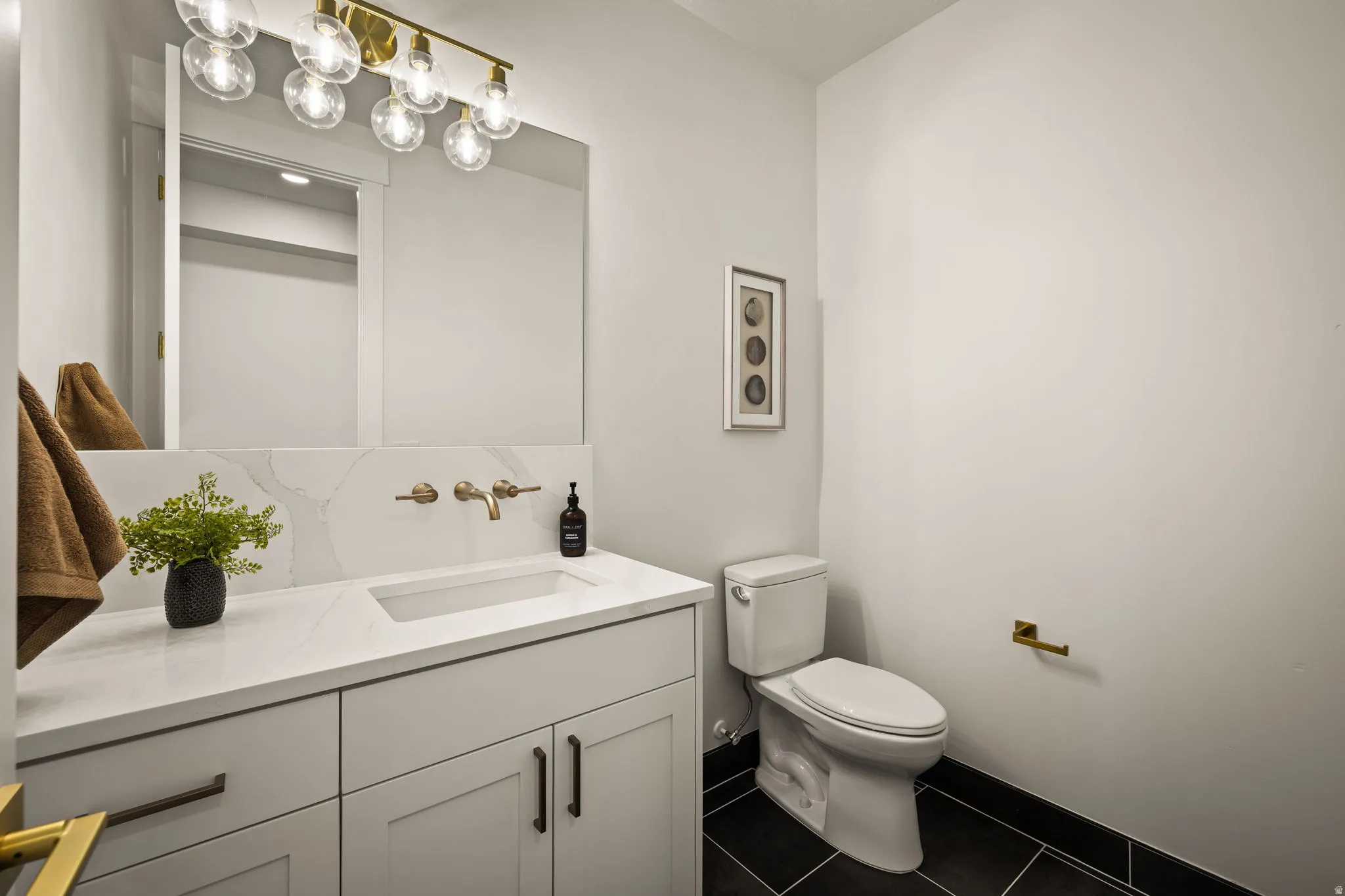 Bathroom featuring a white vanity with integrated sink, gold wall-mounted faucet, and a large rectangular mirror