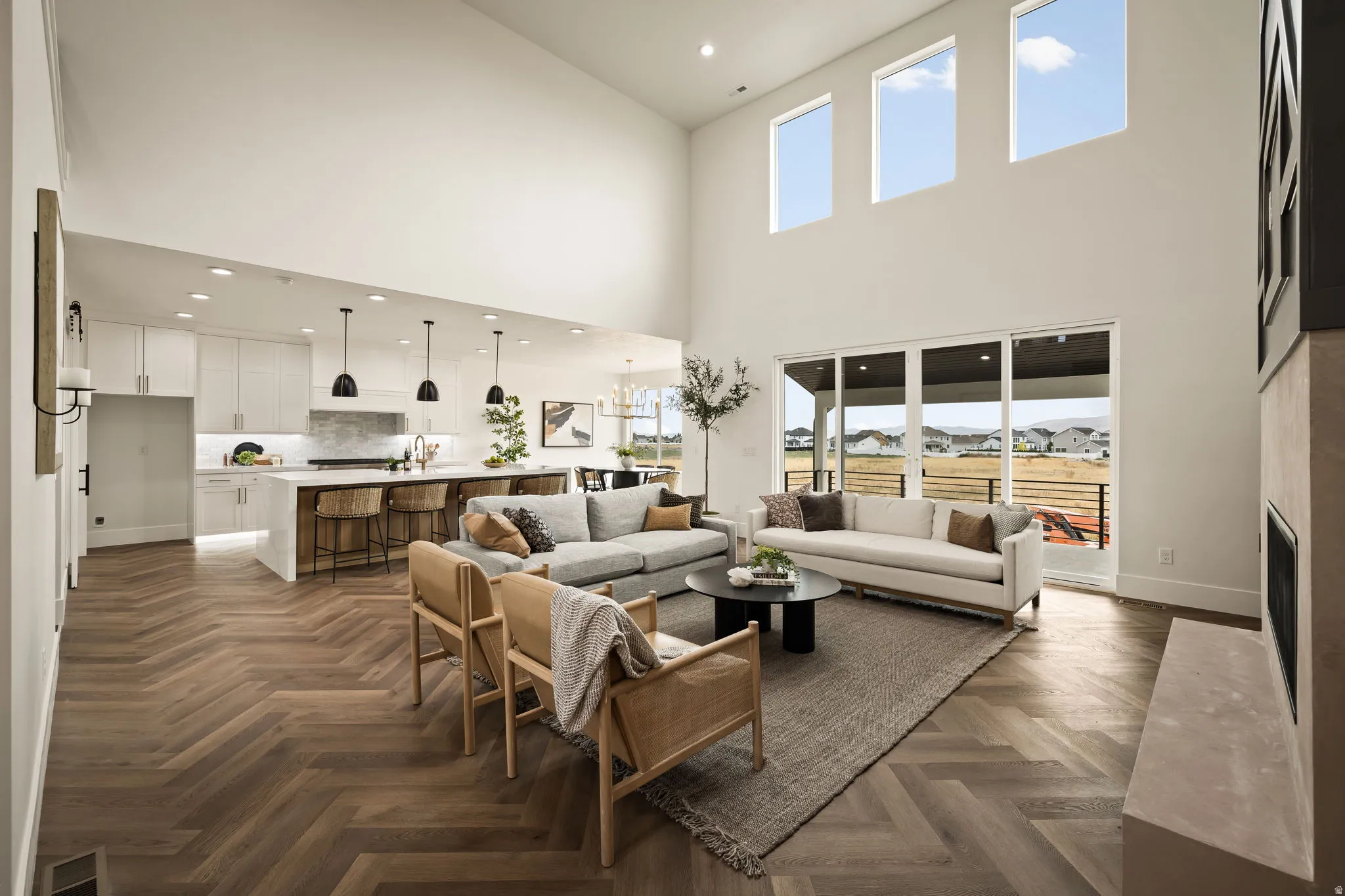 Expansive living area featuring soaring ceilings and herringbone wood-finish flooring