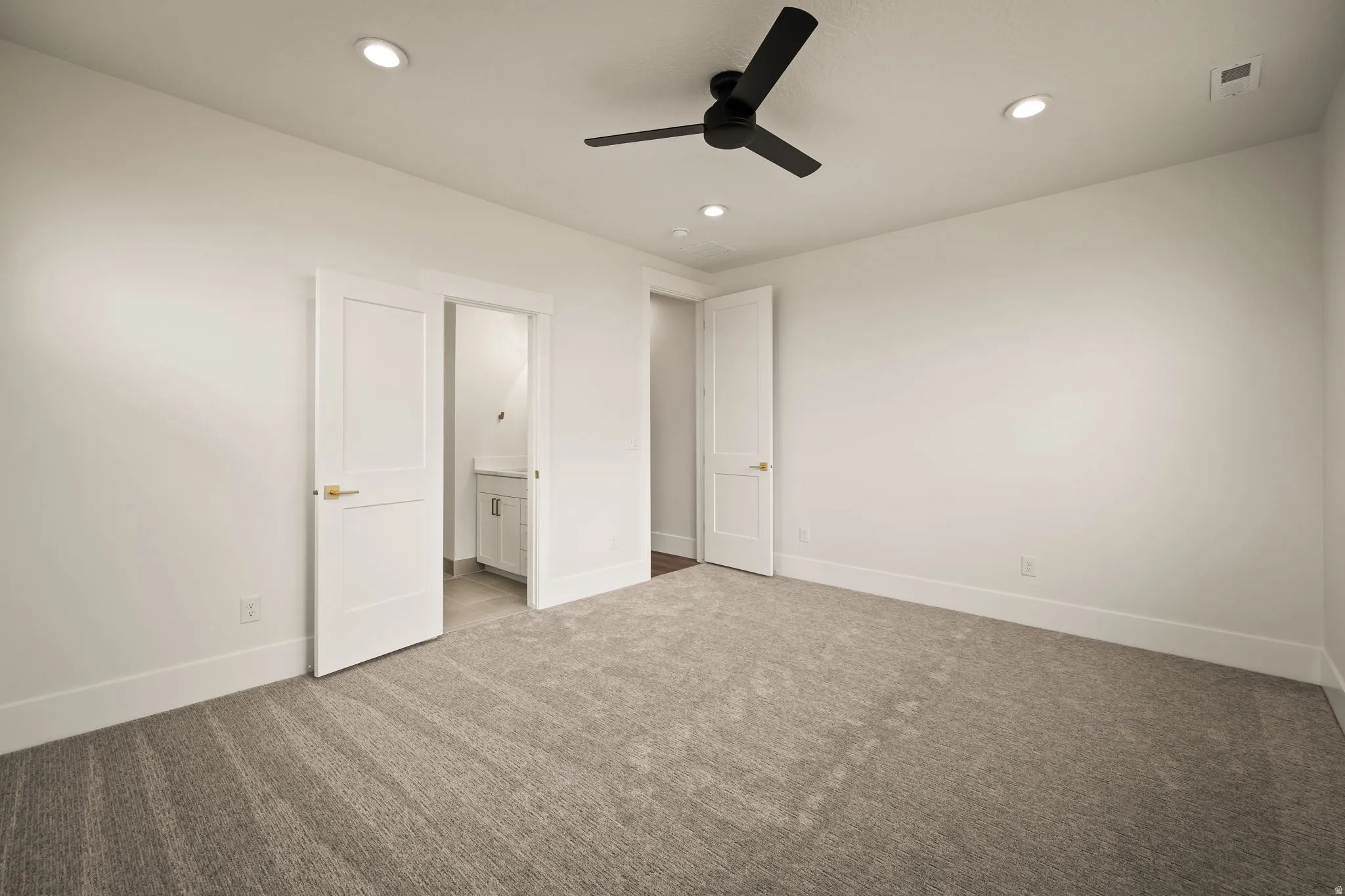 Spacious room featuring neutral carpeting, recessed ceiling lighting, and a modern black ceiling fan