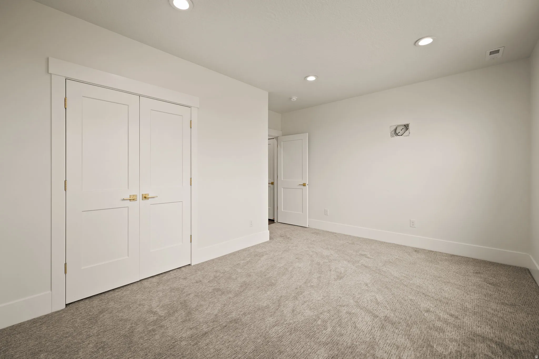 Neutral-toned carpeting extends throughout this room, featuring recessed lighting and white trim work
