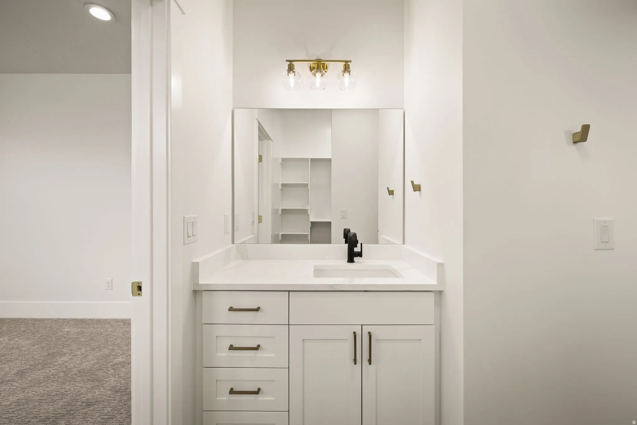 Vanity with stone countertop, integrated sink, and black faucet