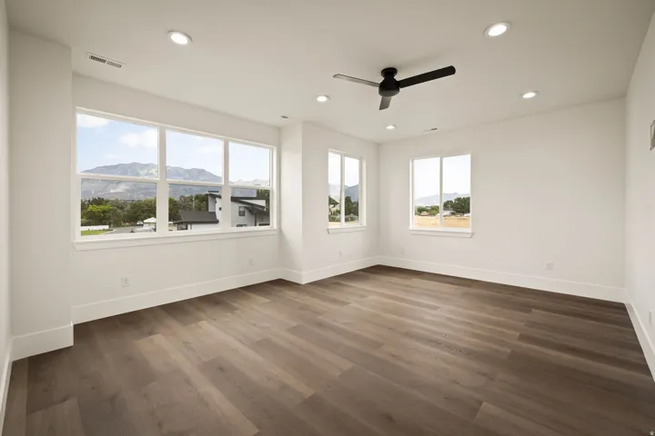 Expansive room featuring wood-finish flooring, multiple windows, a ceiling fan, and recessed lighting