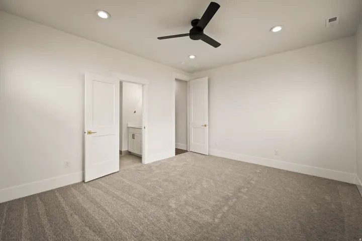 Spacious room featuring neutral carpeting, recessed ceiling lighting, and a modern black ceiling fan