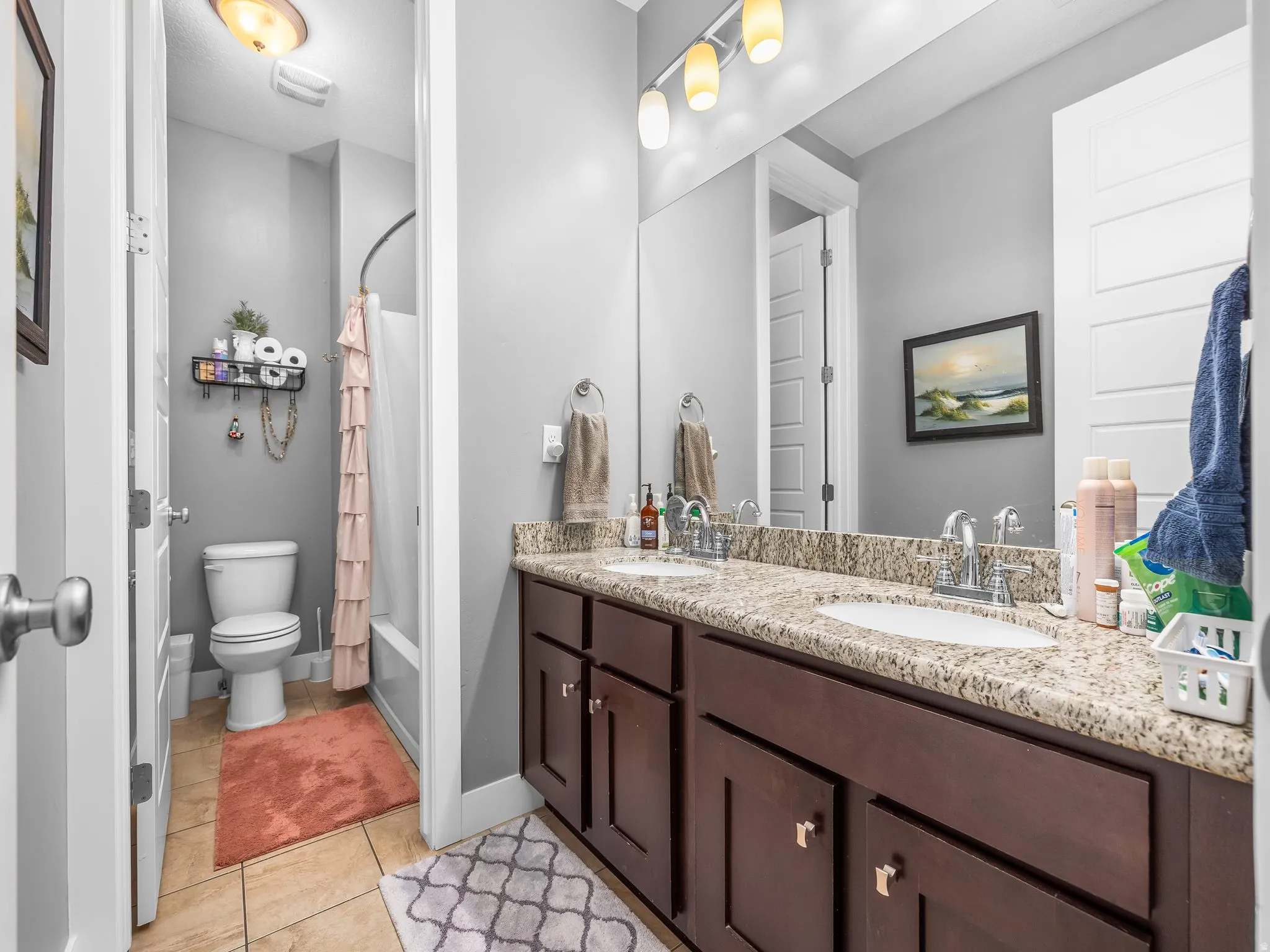 Dual vanity with granite-style countertop and dark wood-finish cabinetry