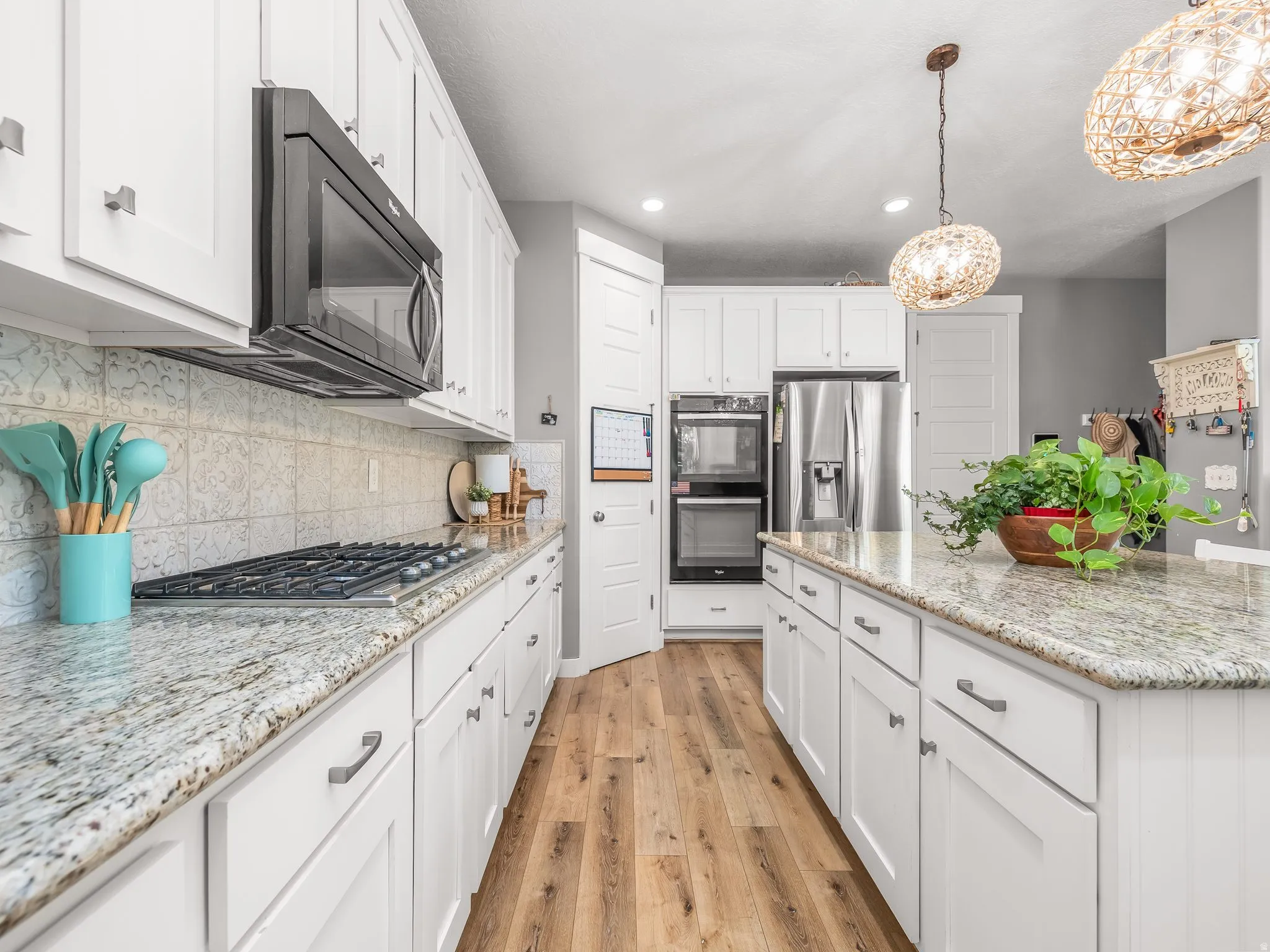 White cabinetry with modern hardware, granite countertops, and patterned tile backsplash