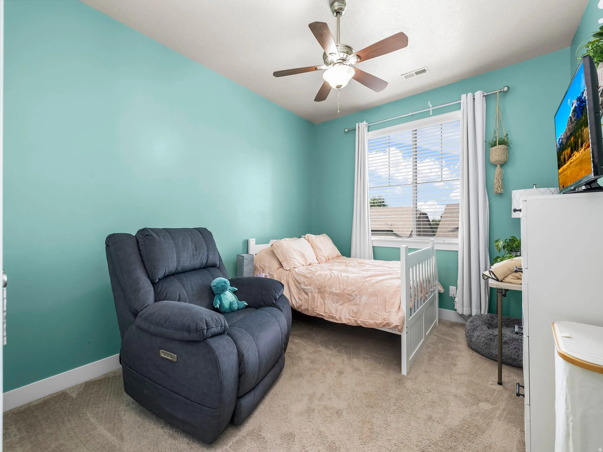 Room featuring light teal walls, carpet flooring, and a ceiling fan with light fixture