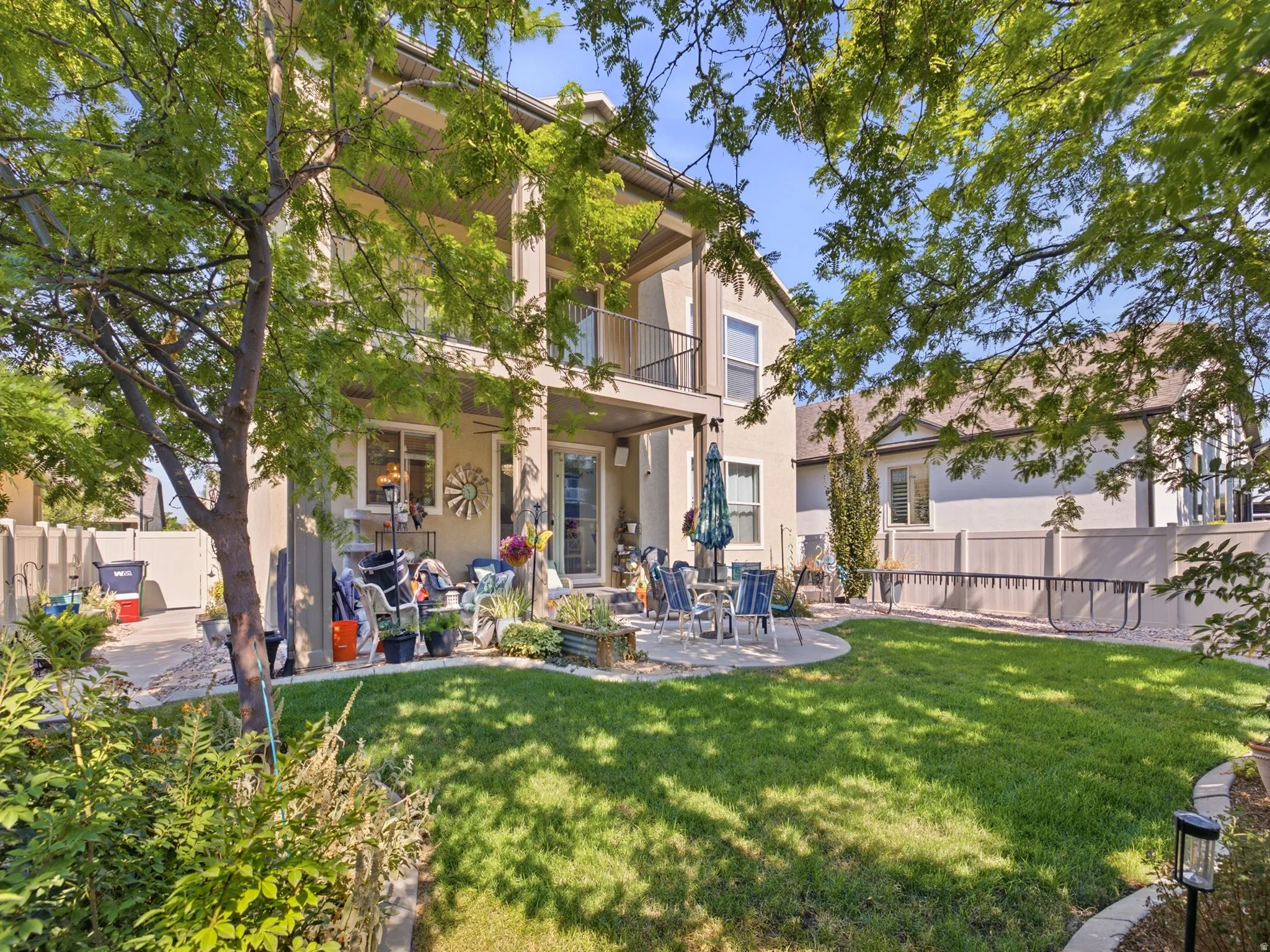 Expansive backyard featuring a lush lawn, mature trees, and a concrete patio