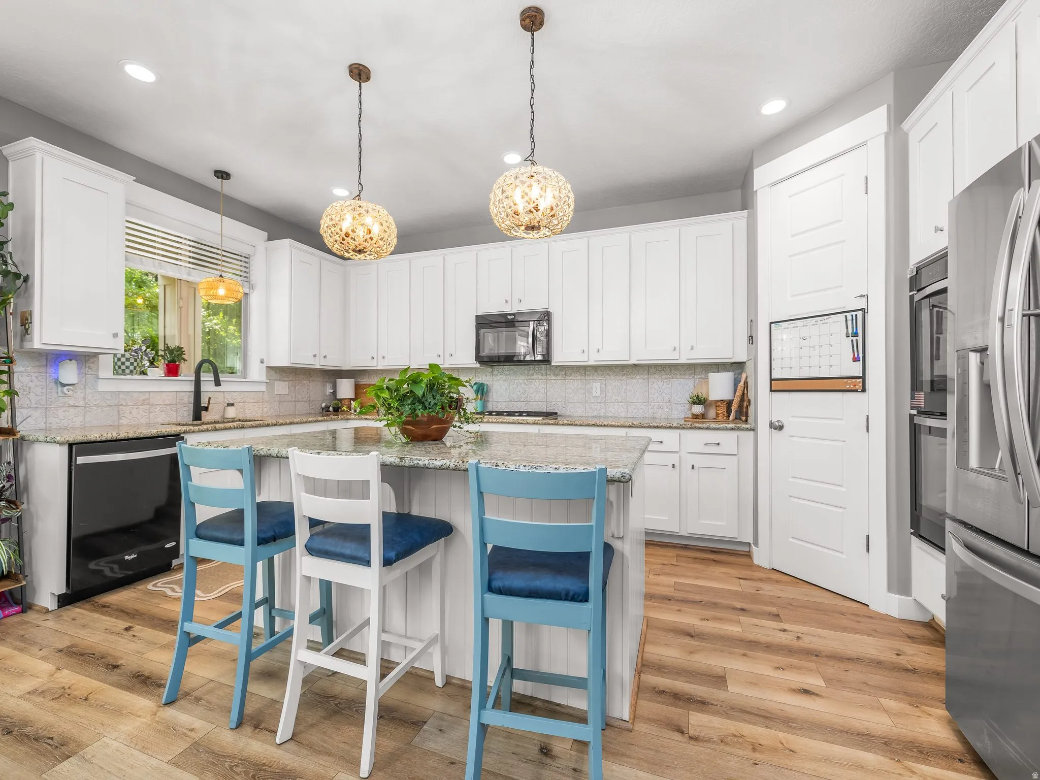 Kitchen featuring a central island with granite countertop, white cabinetry, wood-finish flooring, and recessed lighting