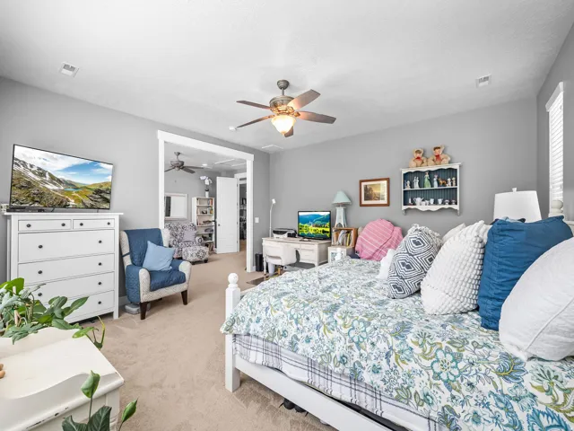 Carpeted interior space featuring light gray walls, a ceiling fan with integrated lighting, and a white-trimmed doorway