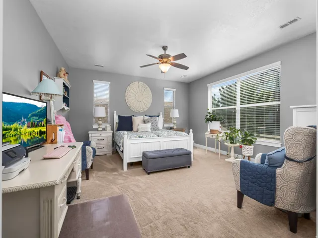 Carpeted room featuring a ceiling fan with integrated lighting, multiple windows with blinds, and white trim throughout