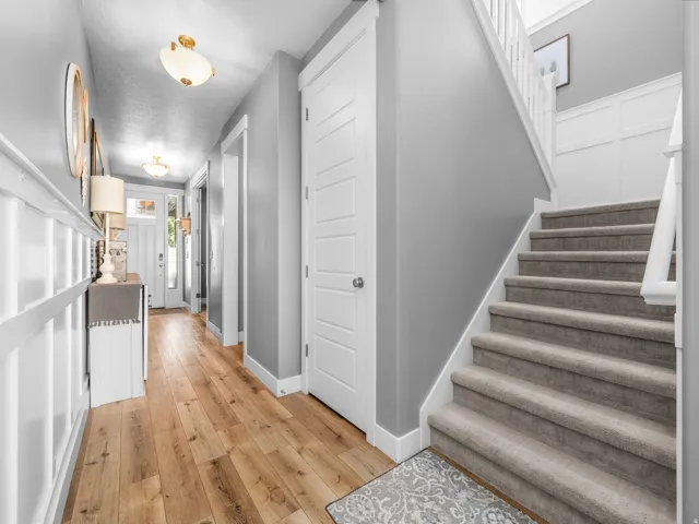 Entryway featuring wood-finish flooring, white wainscoting, and a staircase with light-toned carpet