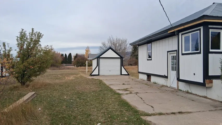 Detached single-car garage featuring a white overhead door and matching siding