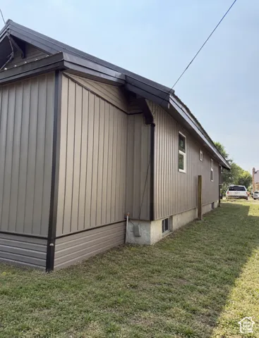 Vertical panel siding with contrasting trim, white-framed windows, and a concrete foundation