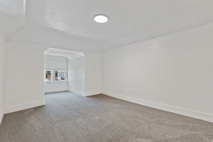 Carpeted room featuring a white ceiling and walls, recessed window area, and a flush-mount ceiling light fixture