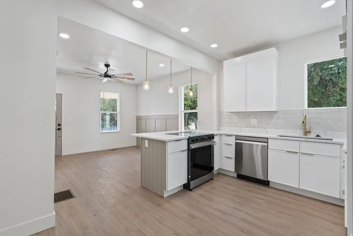 Modern kitchen featuring white cabinetry, stainless steel appliances, light countertops, and a subway tile backsplash