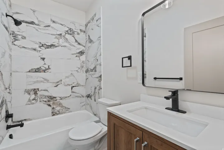Bathroom featuring a white subway tile tub surround with marble-look accents, a built-in bathtub, and a modern vanity with a rectangular sink