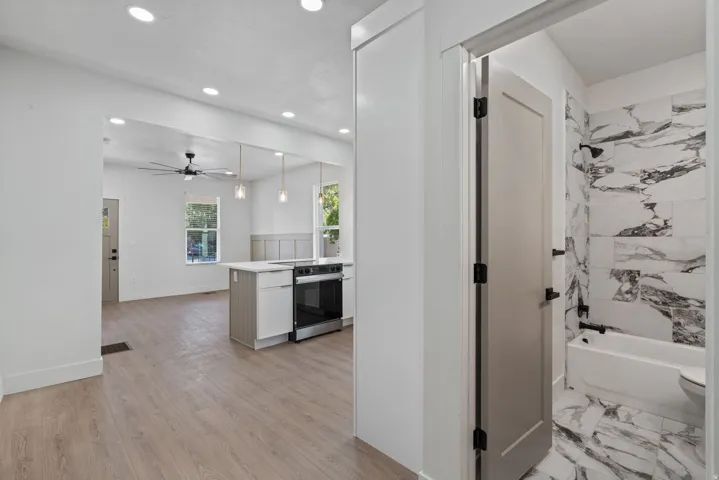 Contemporary bathroom featuring a white bathtub with dark fixtures, striking marble-look tile flooring, and coordinating marble-look tile shower surround