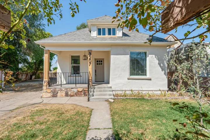 Stucco exterior featuring a prominent front porch with stone accents and wood columns