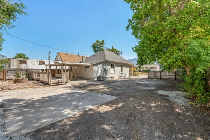 Expansive outdoor area featuring a concrete patio, shaded porch structure, and additional graveled space