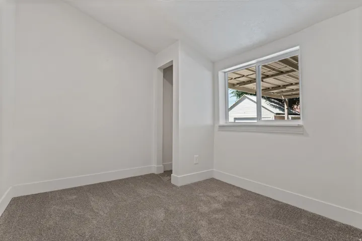 Carpeted room featuring a white interior, white trim, and a window with white framing