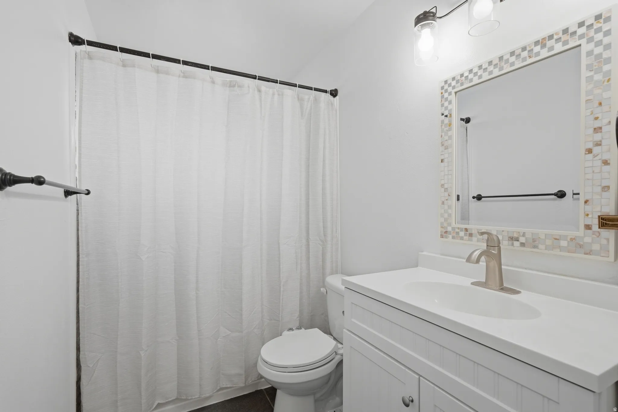 Bathroom featuring a white vanity with integrated sink, brushed nickel faucet, and a tiled mirror frame