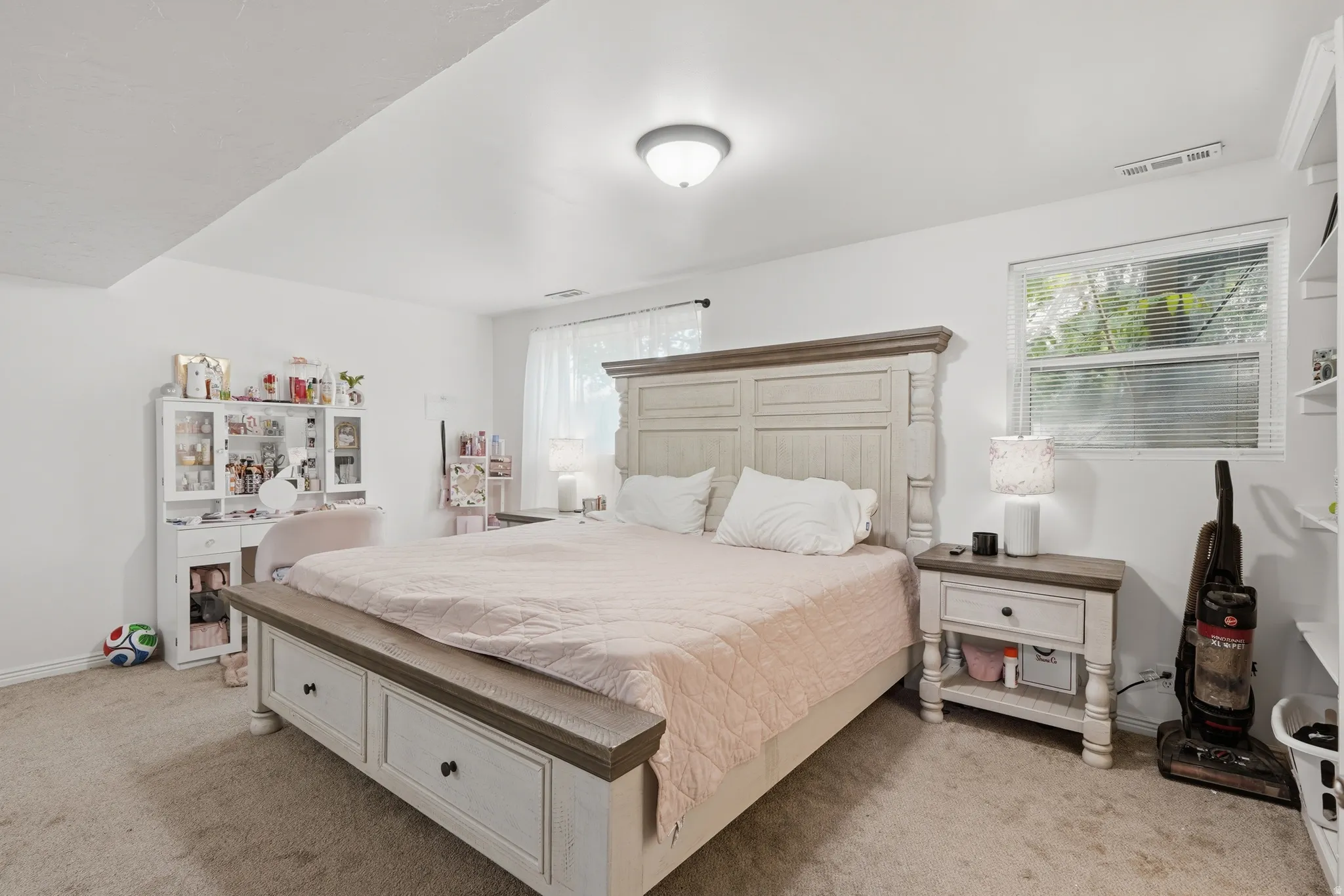 Carpeted bedroom featuring white walls and a large window with blinds
